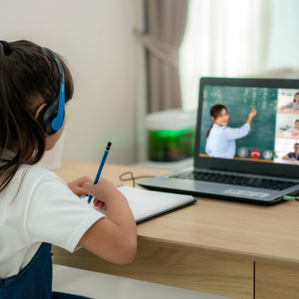 Asian girl student video conference e-learning with teacher and classmates on computer in living room at home. Homeschooling and distance learning ,online ,education and internet.